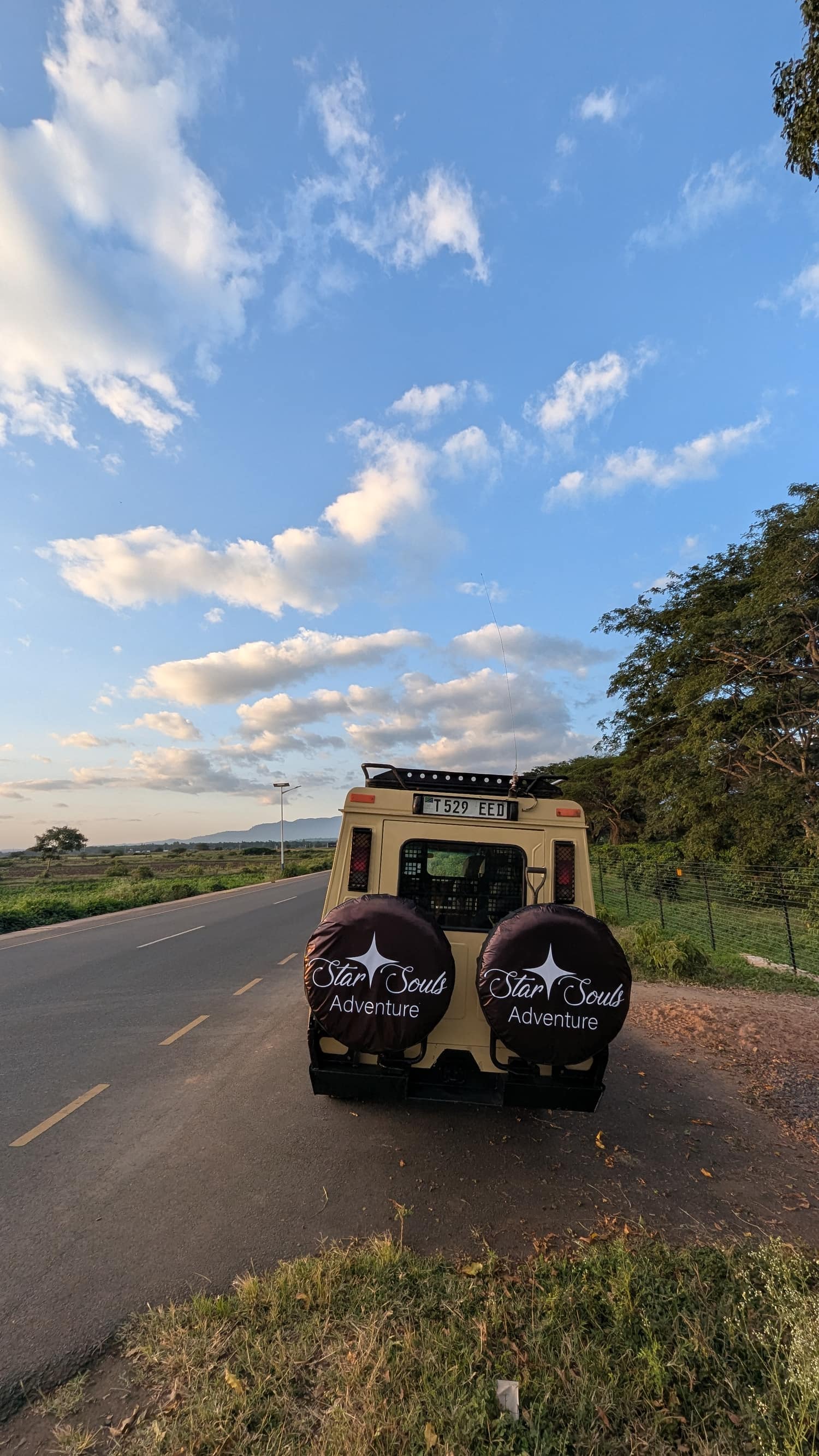 A Star Souls Adventure safari vehicle on the open road under a wide Tanzanian sky